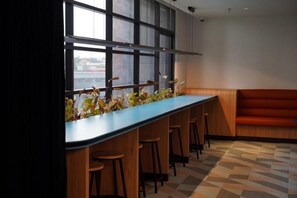 A bar area with a long counter, stools, and a view through large windows. - The Graph Hotel Kuala Lumpur (Kuala Lumpur)