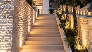 Una scala conduce a un edificio moderno con pareti in pietra e illuminazione esterna.