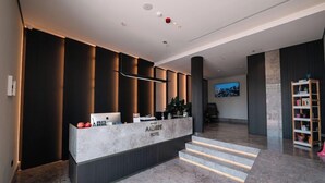Un'area reception di un hotel con un bancone in marmo, una televisione e una scala che conduce ai piani superiori.
