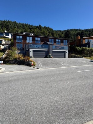 A modern building with a garage entrance, surrounded by a parking lot and greenery. - Highview Vista - Lake views, Outdoor Fireplace, great for families (Queenstown)