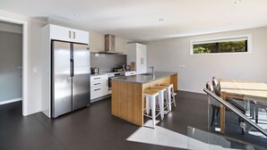 Uma cozinha moderna com geladeira de aço inoxidável, ilha de madeira e banquetas de bar.