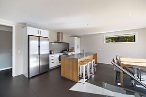 A modern kitchen with a stainless steel refrigerator, wooden island, and bar stools. - Highview Vista - Lake views, Outdoor Fireplace, great for families (Queenstown)