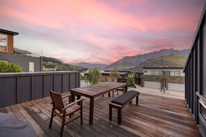 A wooden deck with a table and chairs, overlooking a mountainous landscape. - Highview Vista - Lake views, Outdoor Fireplace, great for families (Queenstown)