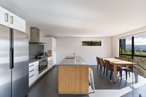 A modern kitchen with a central island, stainless steel appliances, and a dining area with a view. - Highview Vista - Lake views, Outdoor Fireplace, great for families (Queenstown)