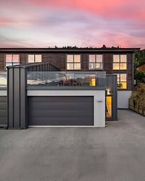 A modern two-story house with a garage, large windows, and a view of the mountains. - Highview Vista - Lake views, Outdoor Fireplace, great for families (Queenstown)