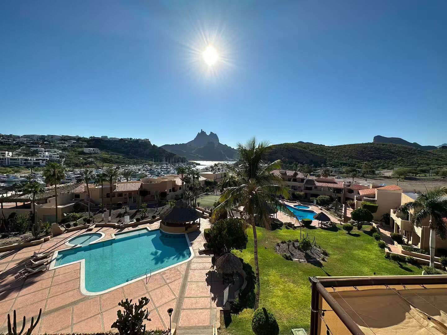 Un complexe hôtelier doté de plusieurs piscines, offrant une vue dégagée sur l’océan et s’inscrivant dans un paysage montagneux.