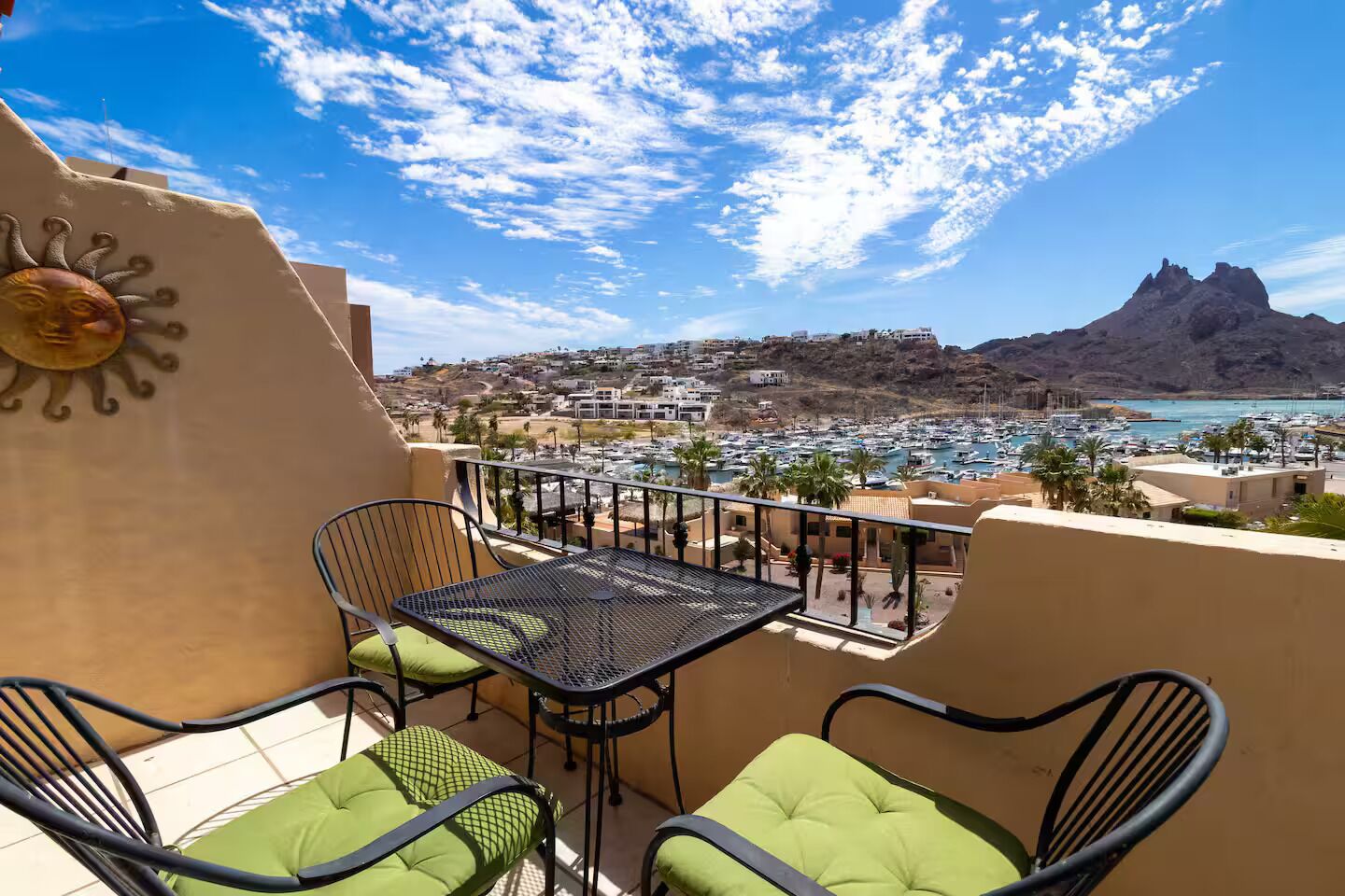 Un balcon avec une table et des chaises, donnant sur une marina et un paysage montagneux.