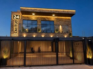Un hotel moderno con fachada de piedra, ventanas amplias y entrada protegida por una reja.