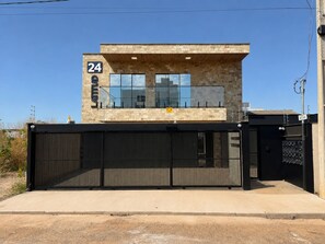 A modern building with a stone facade, numbered 24, and a black metal gate.