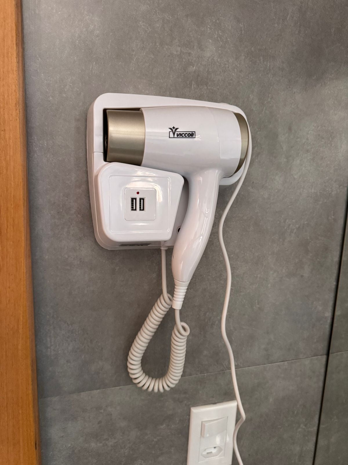 Een haardroger bevestigd aan de muur, met een stopcontact eronder.
