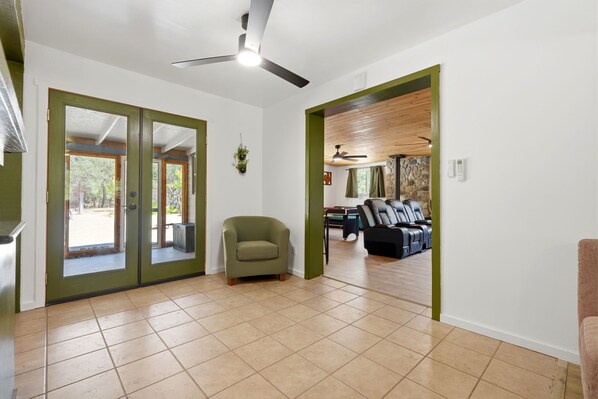 A spacious room with a ceiling fan, a green armchair, and a seating area with multiple chairs. - Gateway to the Sequoia's Home in Three Rivers Game room - Perfect for Groups (Three Rivers)
