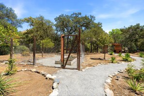 Un jardin clos, avec un chemin de gravier, des poteaux en bois et une petite construction.