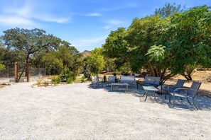 An outdoor seating area with tables and chairs, surrounded by trees and a gravel ground. - Gateway to the Sequoia's Home in Three Rivers Game room - Perfect for Groups (Three Rivers)