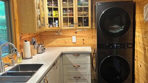 A compact kitchen with wooden cabinets, a double-door refrigerator, and a built-in washing machine.