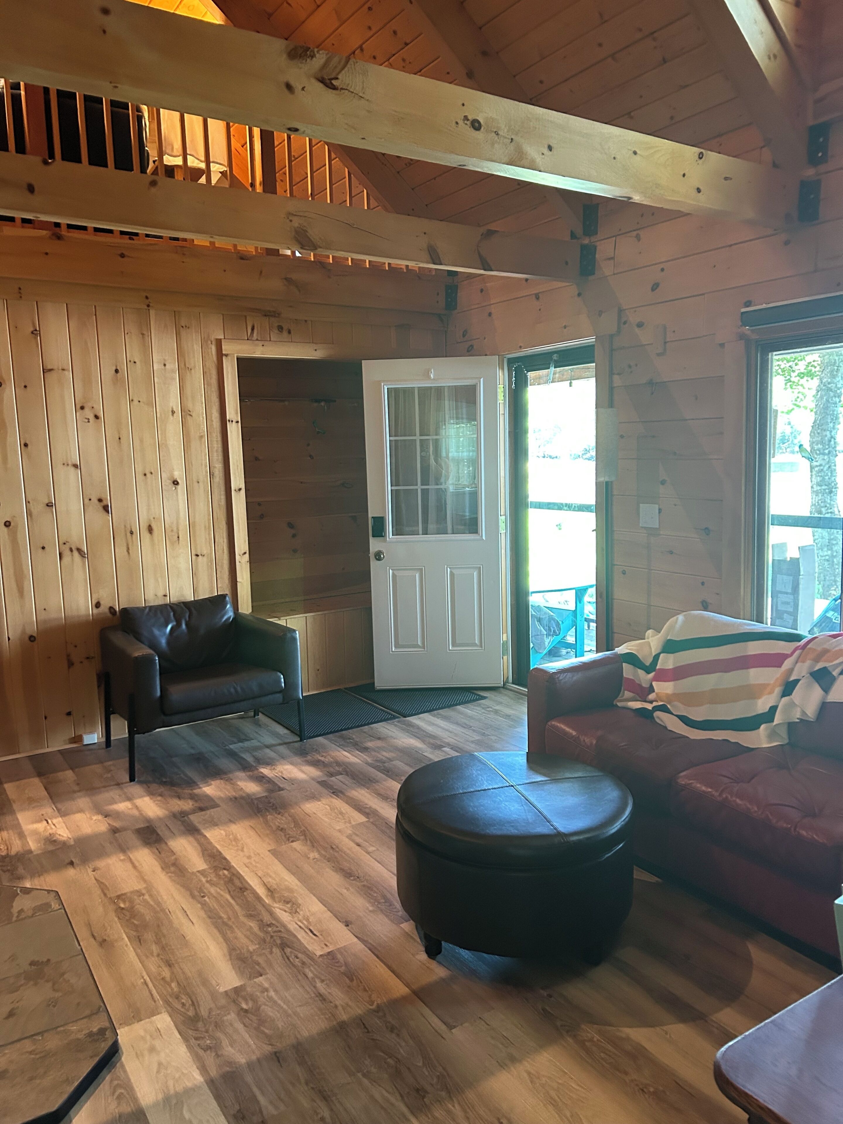 A wooden interior with a door, two sofas, and a bench.