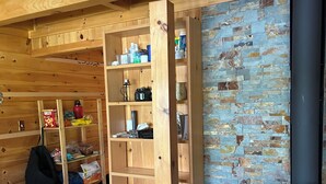 A cozy room with a wooden bookshelf, a brick wall, and a wood-burning stove.