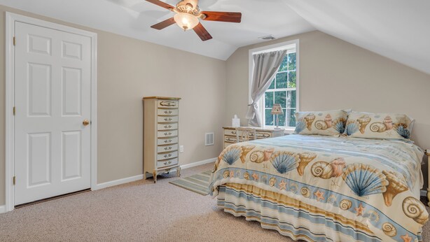 A bedroom with a bed, a dresser, a ceiling fan, and a window with curtains. - Saybrook Point Pool House (Old Saybrook)