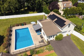 A residential property with a swimming pool, solar panels, and a fenced yard.