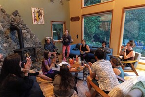 A group of people seated in a room with a stone wall, a fireplace, and large windows. - Riverfront A-Frame with Hot Tub, Game Room and Fire Pit - Sleeps 10, Dogs OK (Granite Falls)