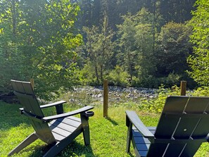 Two Adirondack chairs facing a river with a forest backdrop. - Riverfront A-Frame with Hot Tub, Game Room and Fire Pit - Sleeps 10, Dogs OK (Granite Falls)