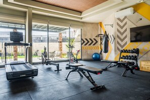 Un gimnasio con equipo de ejercicio, televisión y un amplio ventanal.