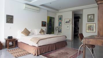 A bedroom with a bed, bedside table, and a fan. There is a door leading to a closet.