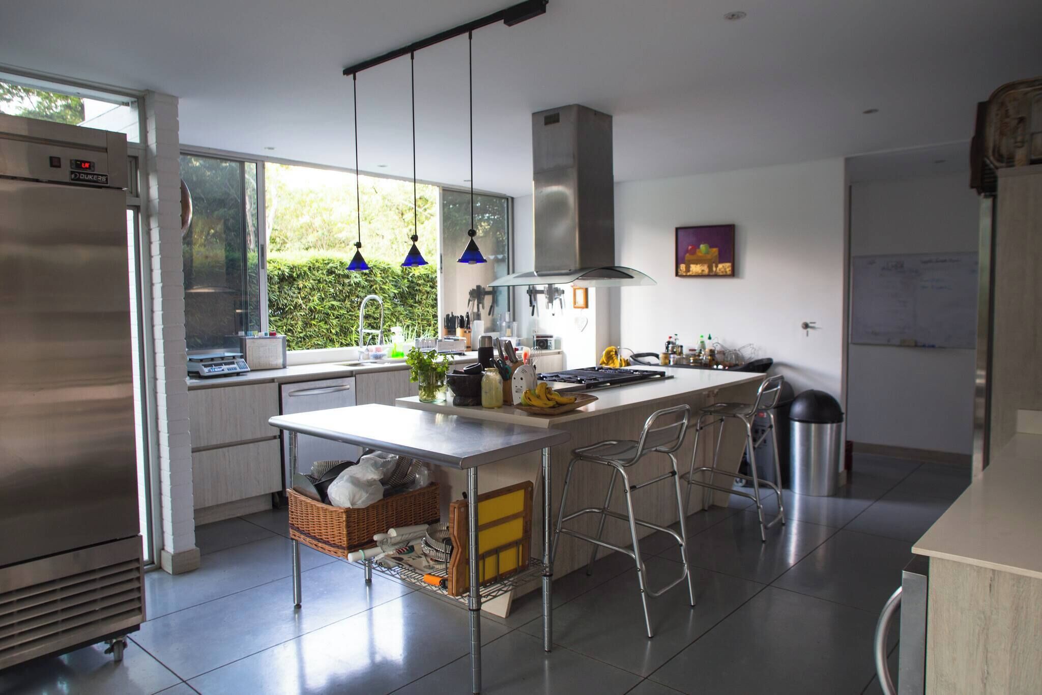 Una cocina moderna con una isla central, electrodomésticos de acero inoxidable y vistas a zonas verdes.