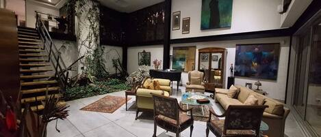 A spacious living room with a high ceiling, a staircase, and a view of the outdoors.