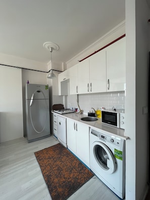A modern kitchen with white cabinets, stainless steel appliances, a built-in oven, microwave, and dishwasher.