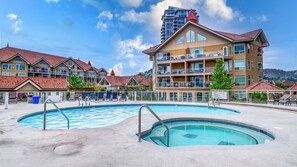 A hotel with a swimming pool, multiple balconies, and a view of a mountain. - Your Ultimate Okanagan Lakeside Escape | Walk-Out Patio & Resort Amenities (Kelowna)