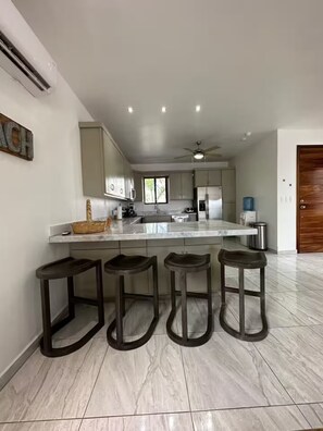 A modern kitchen with a central island, bar stools, and a ceiling fan. - Modern home close to pickleball, beach, pool (La Manga)