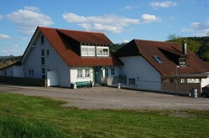 Ein zweigeschossiges Haus mit rotem Ziegeldach, einer grünen Tür und einer kleinen angebauten Garage.