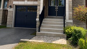Ein zweistöckiges Haus mit einer Steinfassade, einer dunkelblauen Haustür und einer Garage.
