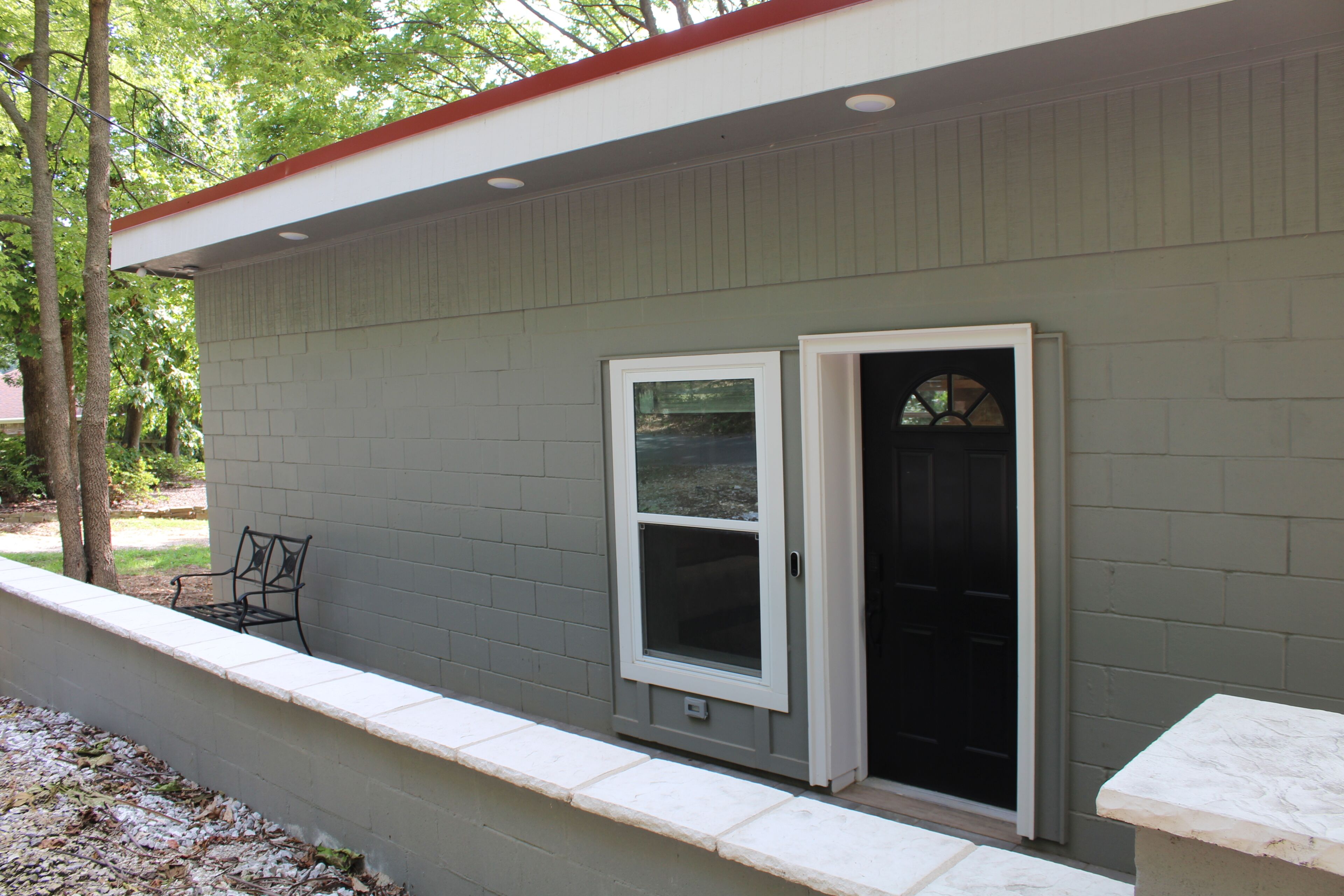 A building with a grey exterior, a white window frame, and a black door with a glass panel.
