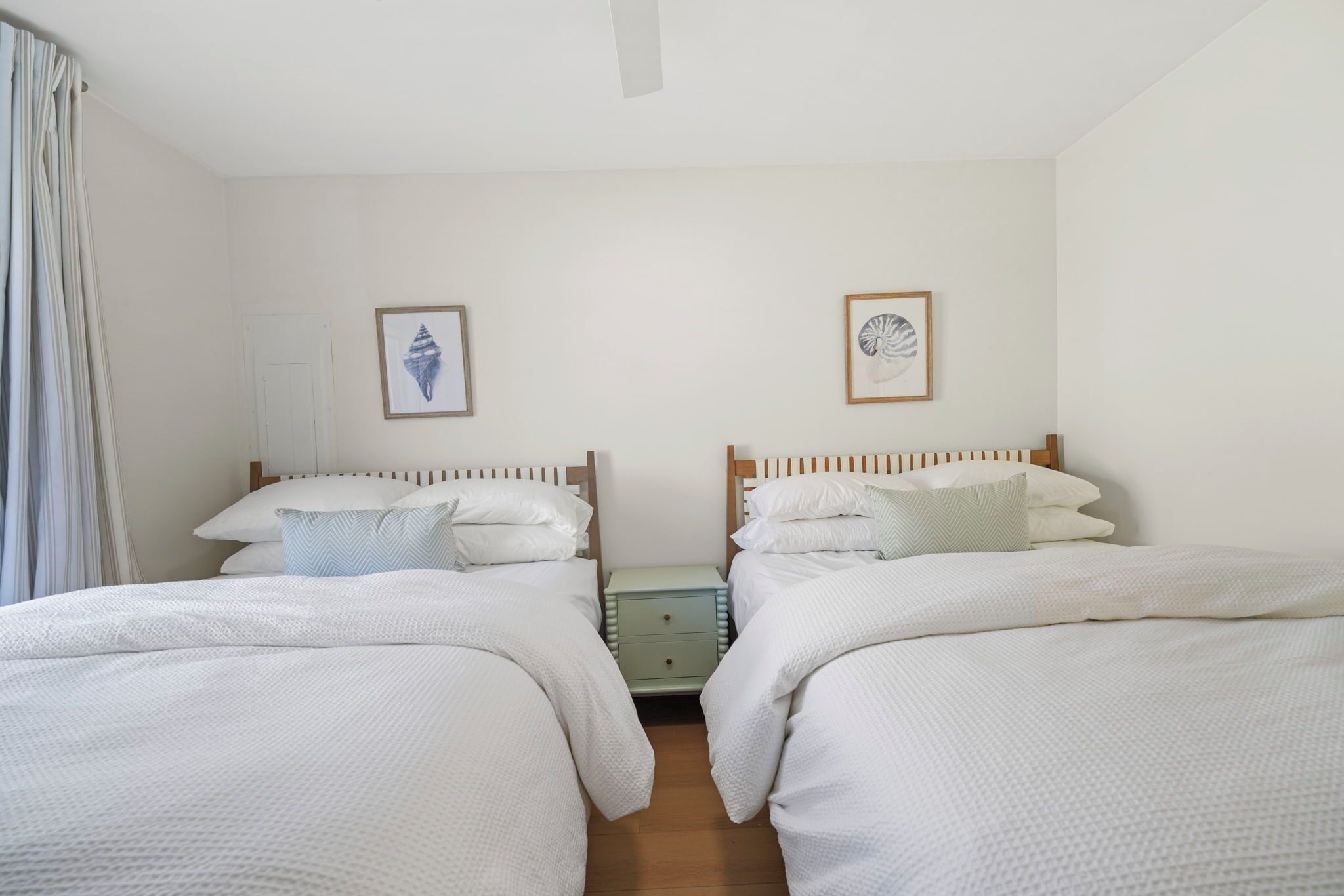 Une chambre double avec deux lits, une table de chevet et un mur décoré de tableaux encadrés.