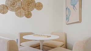 Et moderne interiør med et rundt bord, beige polstrede siddepladser og dekorative billeder på væggen.