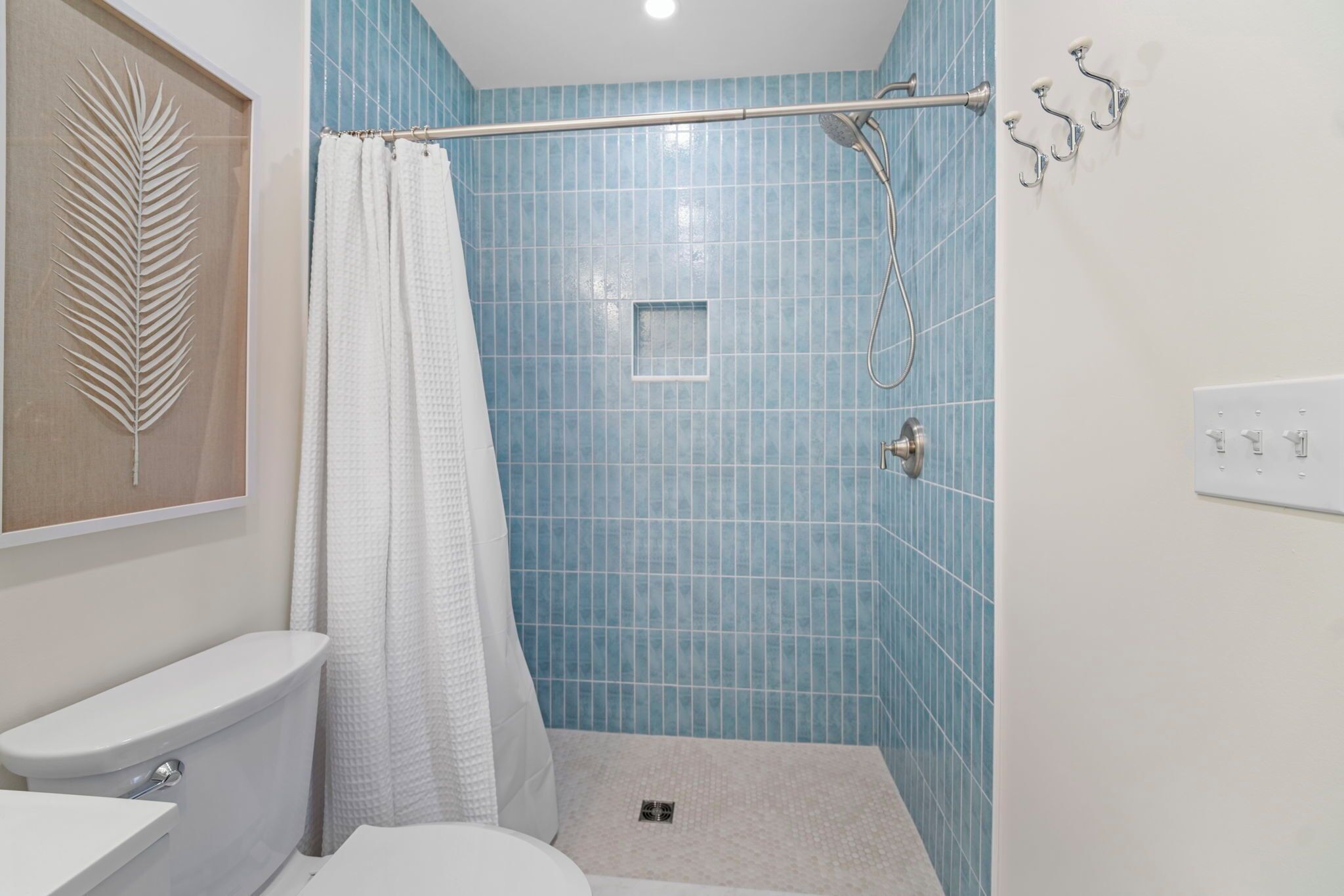 A bathroom with a toilet, a shower with a glass door, and a towel rack.