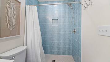 A bathroom with a toilet, a shower with a glass door, and a towel rack.