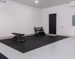 A gym with a bench, dumbbells, and a door. - Stone Peak Mountain Retreat - New w/ ac (Driggs)