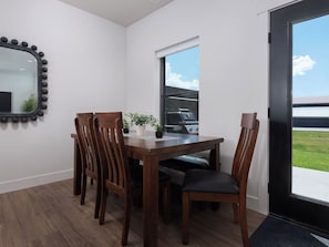 A dining area with a wooden table and chairs, a potted plant, and a view of a grill outside. - Stone Peak Mountain Retreat - New w/ ac (Driggs)