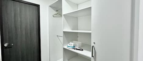 A walk-in closet with white shelving, a dark wooden door, and a light-colored floor.