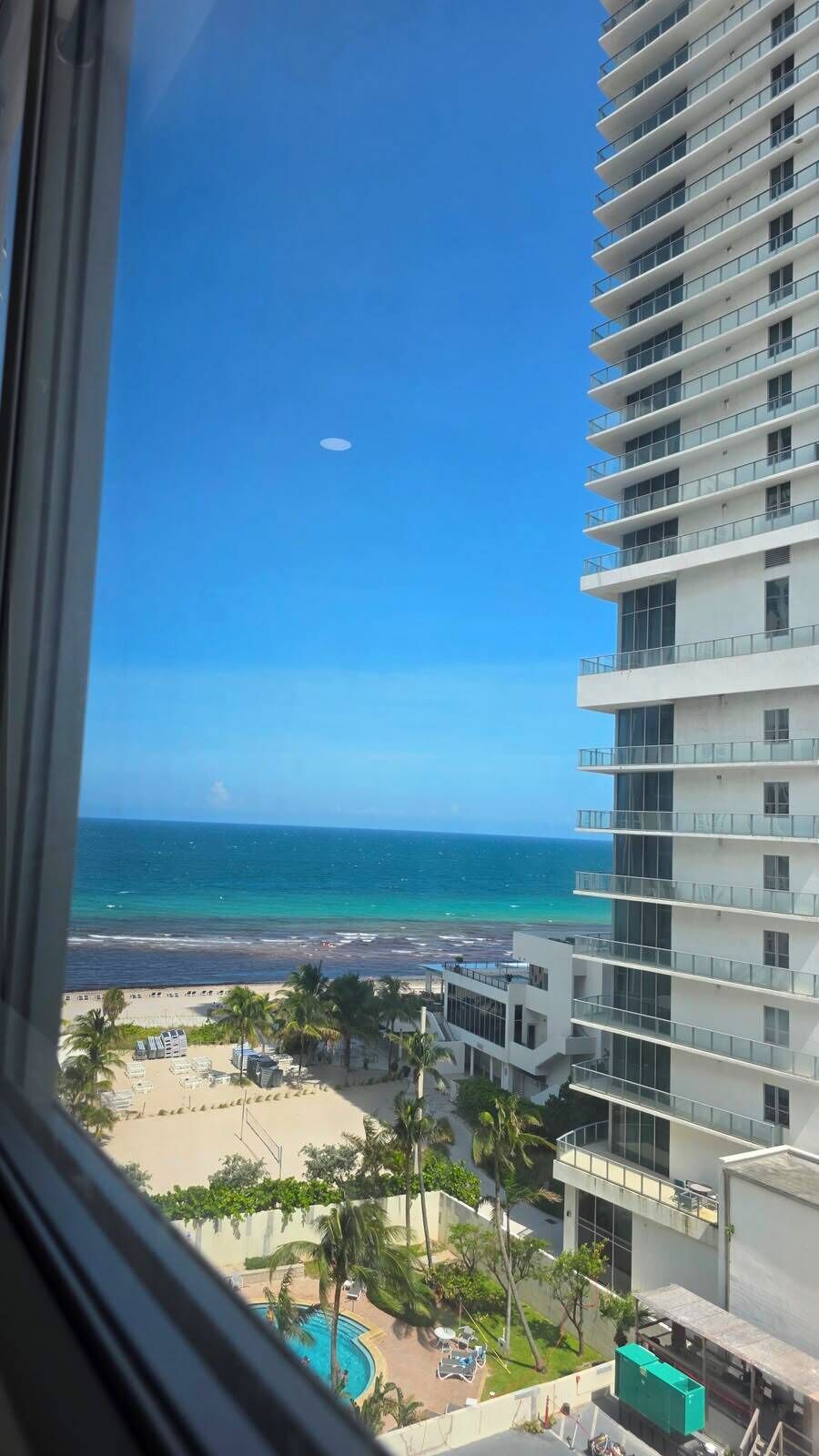 A high-rise building with multiple balconies overlooking a beach and ocean.