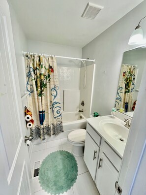 Un bagno con vasca, water, lavandino e specchio.