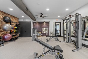 A gym with exercise equipment, a wall-mounted rack with balls, and a ceiling fan. - Stylish 1 King BR suite-Domain Gym, Pool & Parking (Austin)