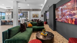 Ein modernes Interieur mit einem grünen Ecksofa, einem runden Couchtisch und einem großen abstrakten Gemälde an der Wand.
