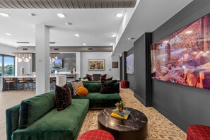 Ein modernes Interieur mit einem grünen Ecksofa, einem runden Couchtisch und einem großen abstrakten Gemälde an der Wand.