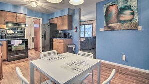 Eine moderne Küche mit Holzschränken, Edelstahlgeräten und einem Essbereich mit Tisch und Stühlen.