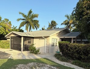 A single-story house with a covered porch, a garage, and a well-maintained lawn. - 2-bedroom bungalow in peaceful George Town with AC (George Town)