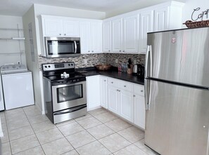 A kitchen with white cabinets, stainless steel appliances, and a tiled floor. - 3-bedroom bungalow in peaceful George Town with AC (George Town)