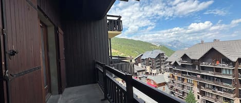 Un edificio de madera con balcón que da a una zona montañosa con varios edificios.